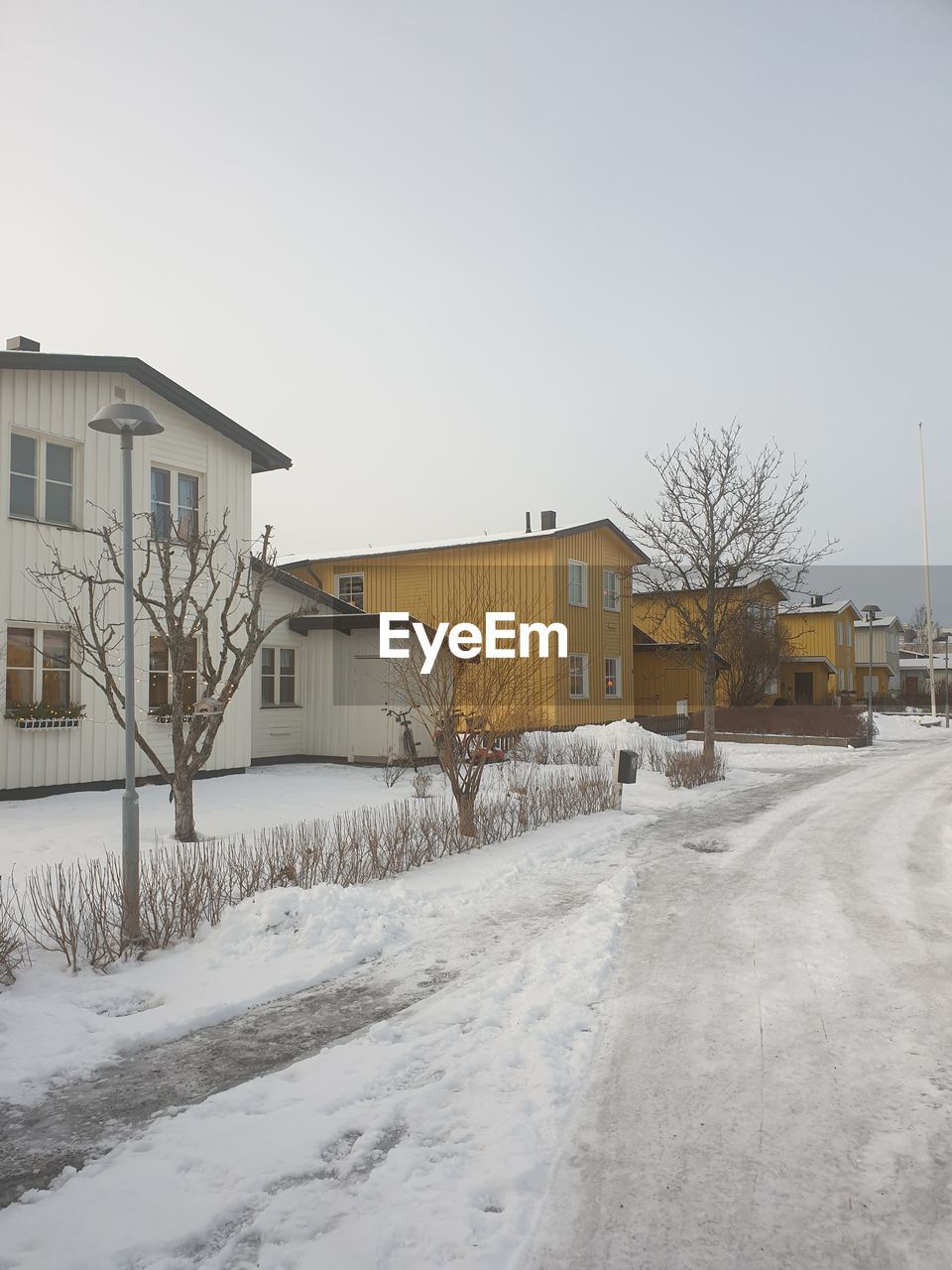 Snow covered houses by buildings against clear sky