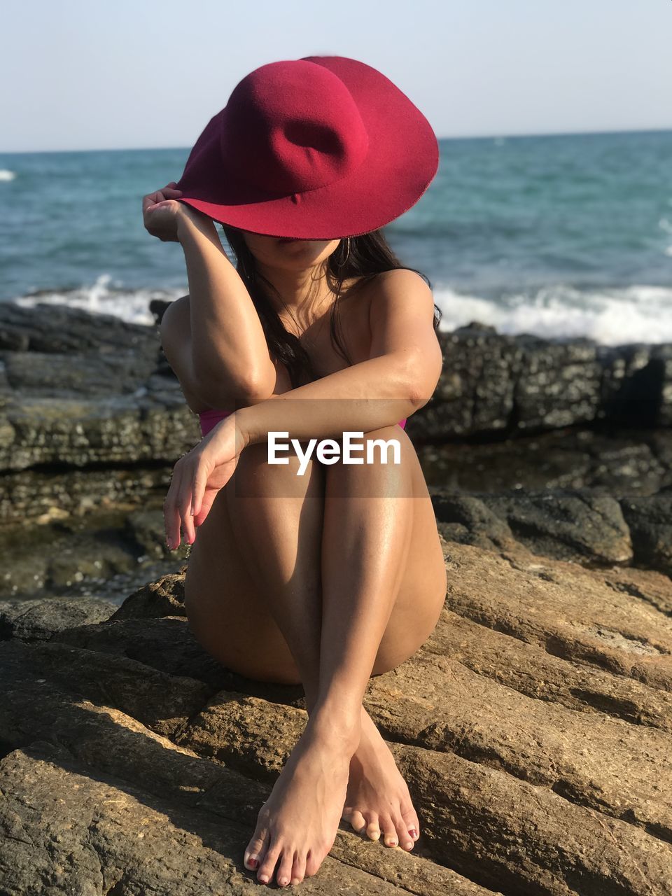 Woman sitting on beach against sea