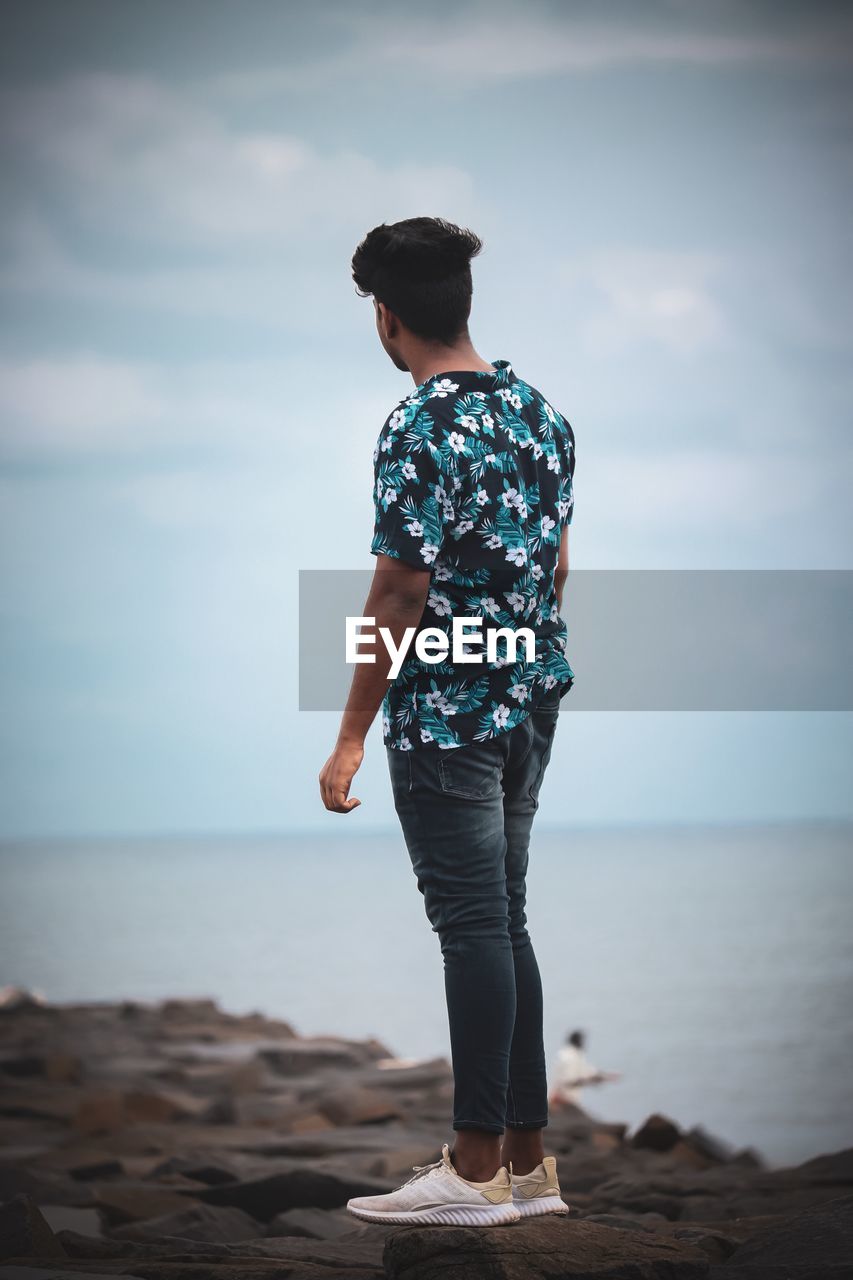 Man standing at beach against sky