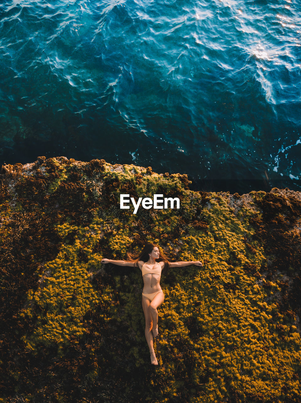 HIGH ANGLE VIEW OF WOMAN WITH ARMS OUTSTRETCHED IN SEA