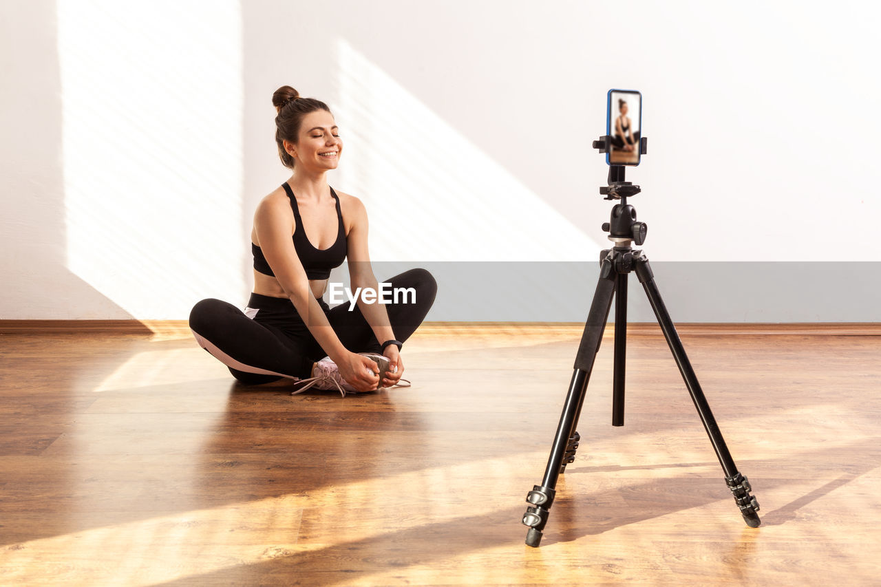 WOMAN SITTING ON WOODEN FLOOR