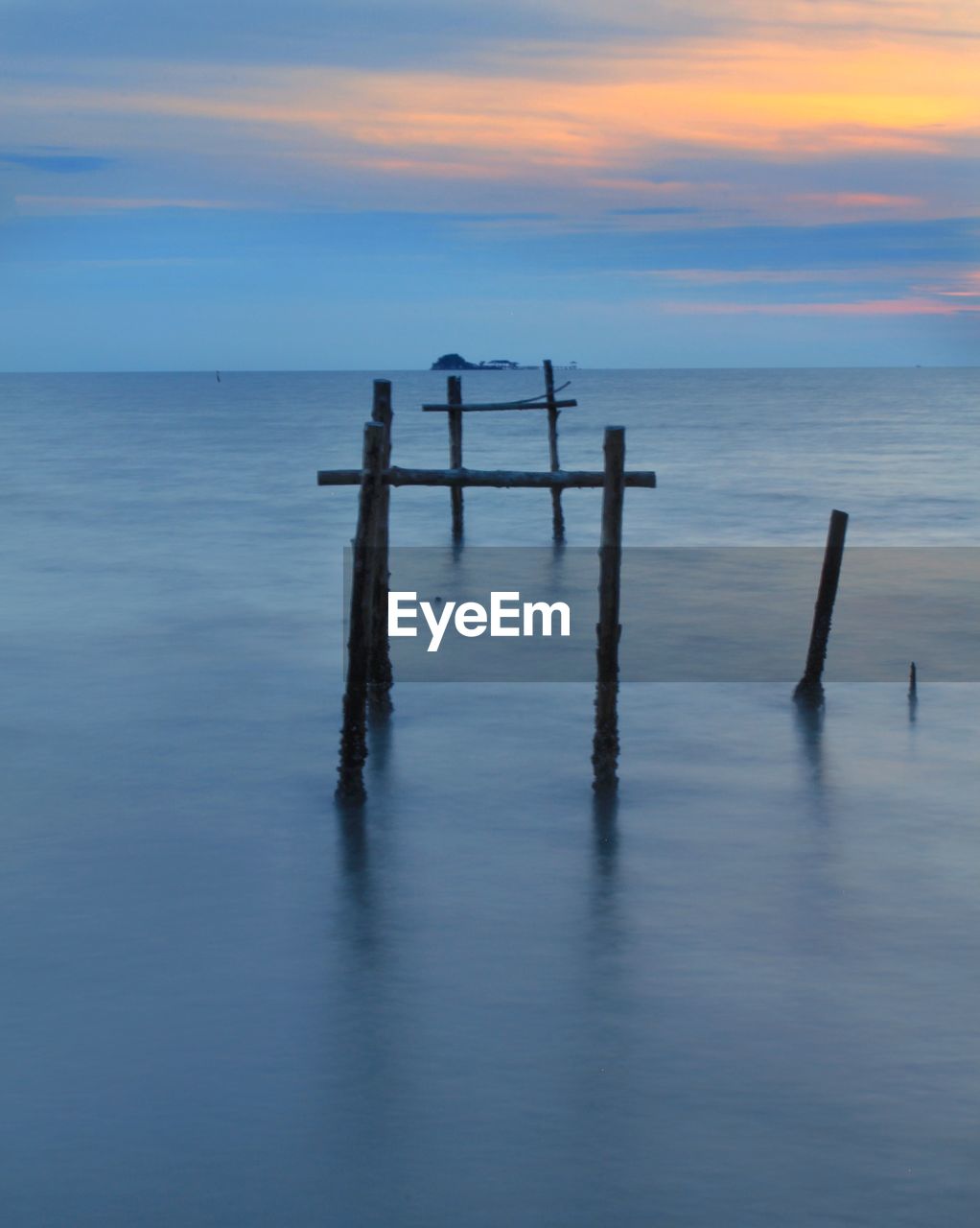 WOODEN POSTS IN SEA AGAINST SKY
