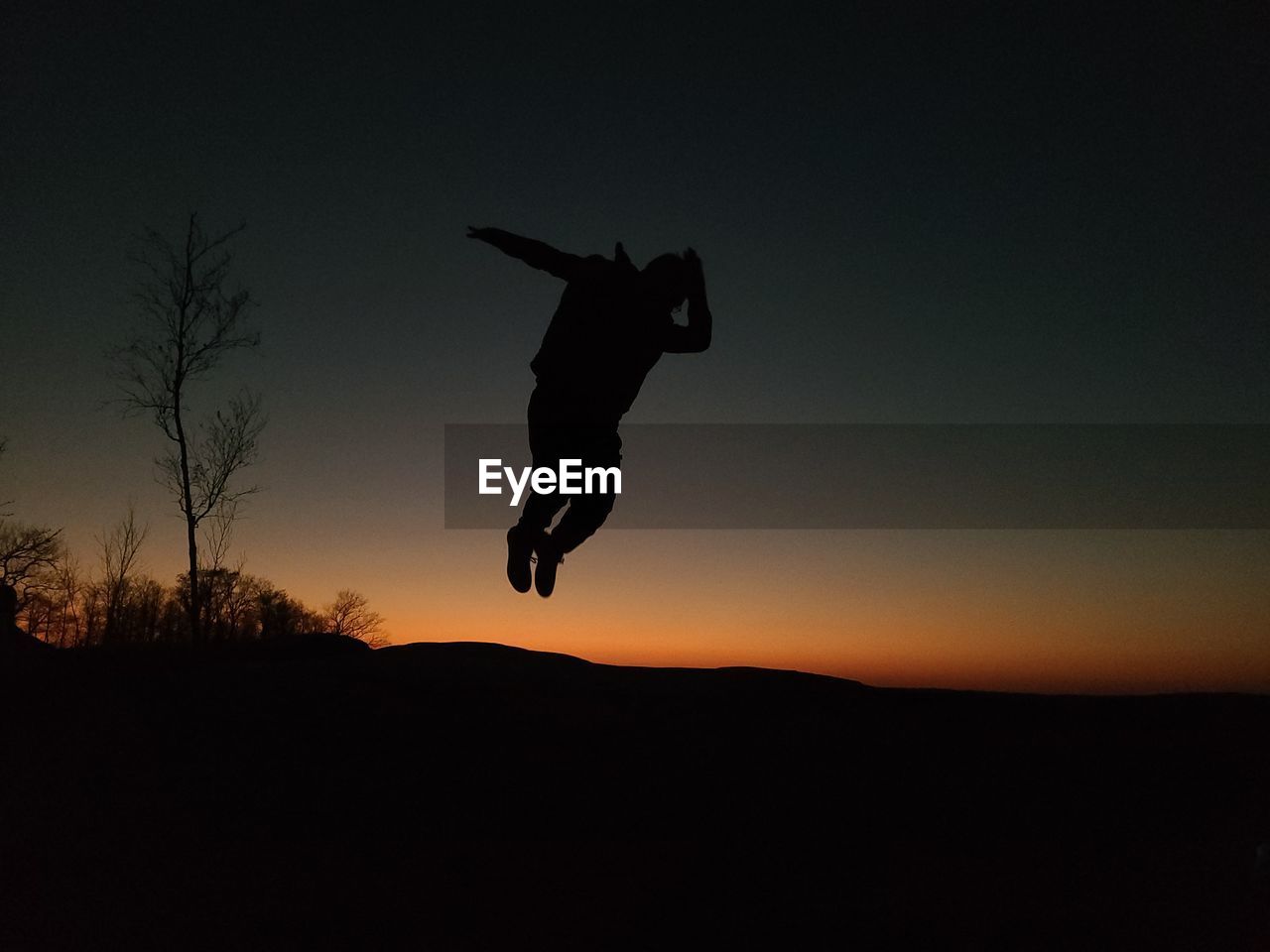 SILHOUETTE OF MAN JUMPING AT SUNSET