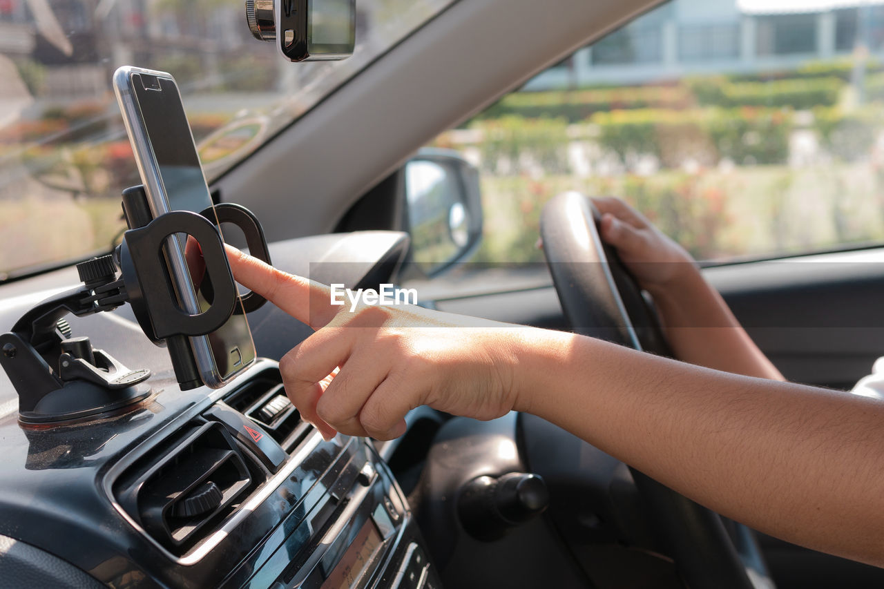 Cropped hands of man using global positioning system while driving car