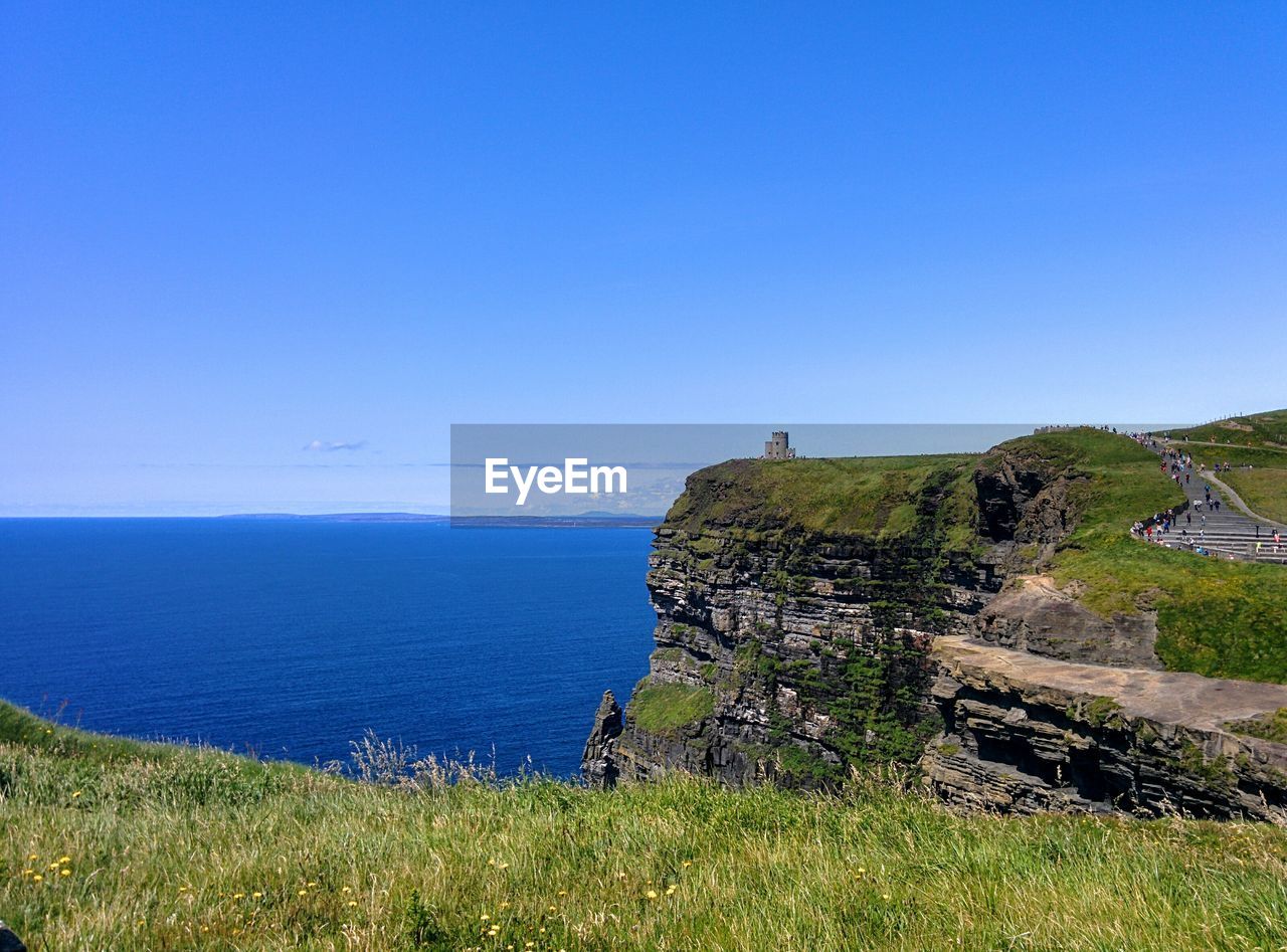 Scenic view of cliff and sea against blue sky