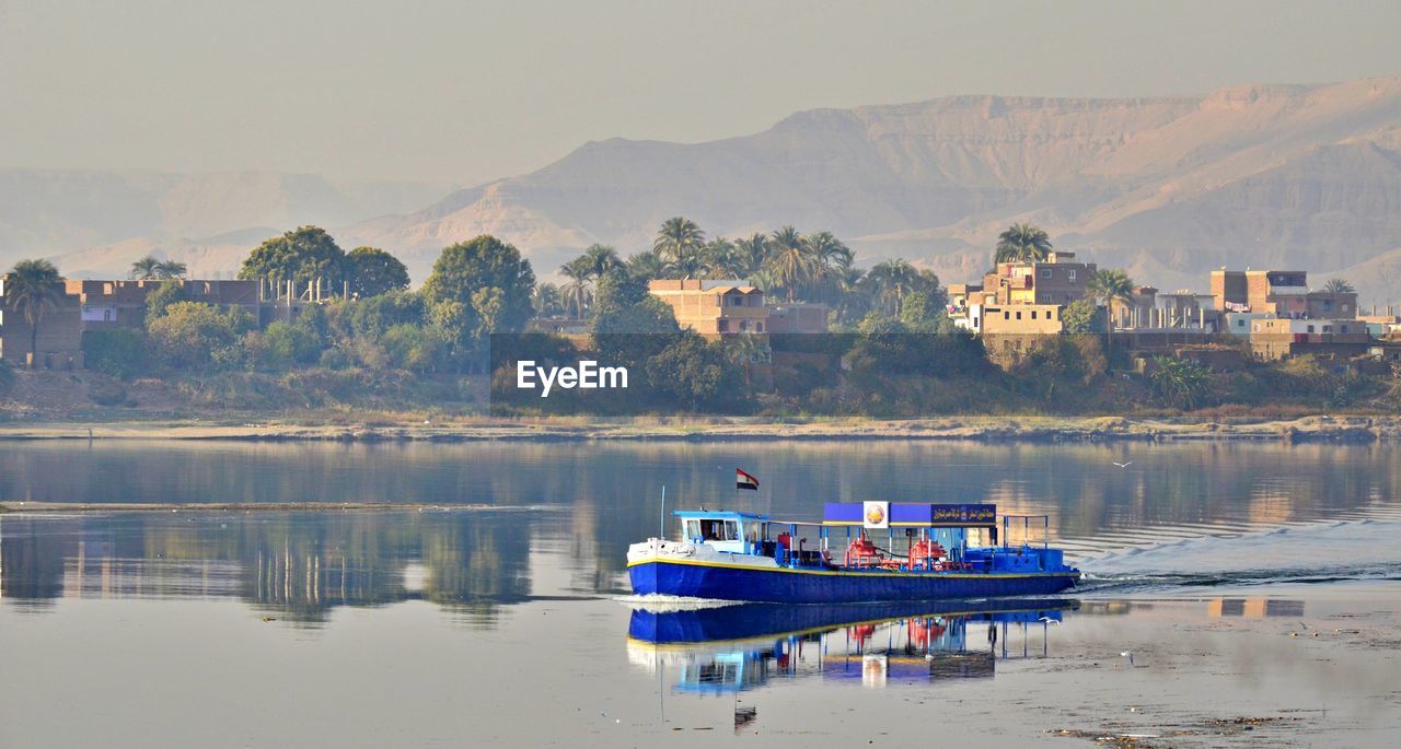 BOAT MOORED IN LAKE AGAINST SKY