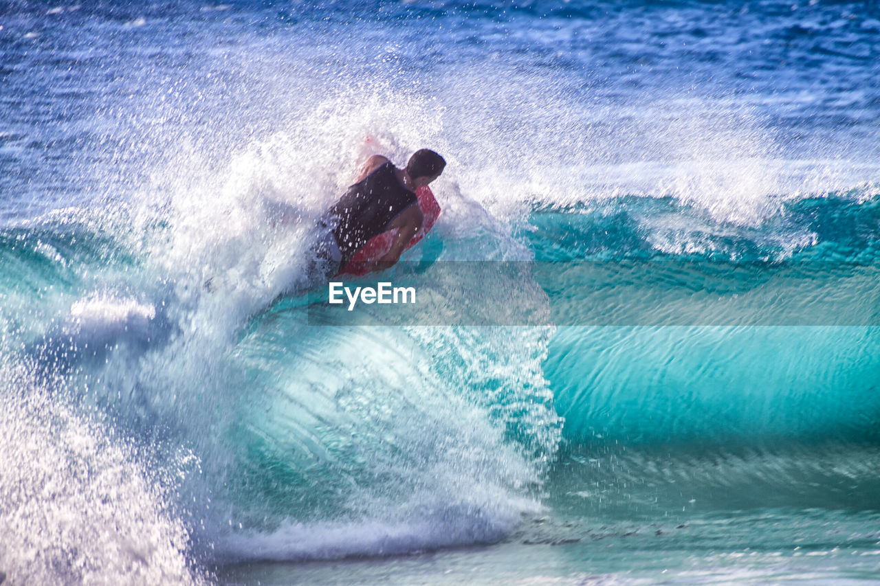 Man surfing on wave in sea