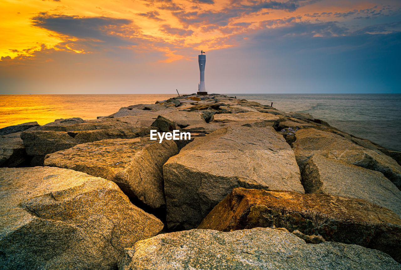 LIGHTHOUSE BY SEA AGAINST SKY AT SUNSET