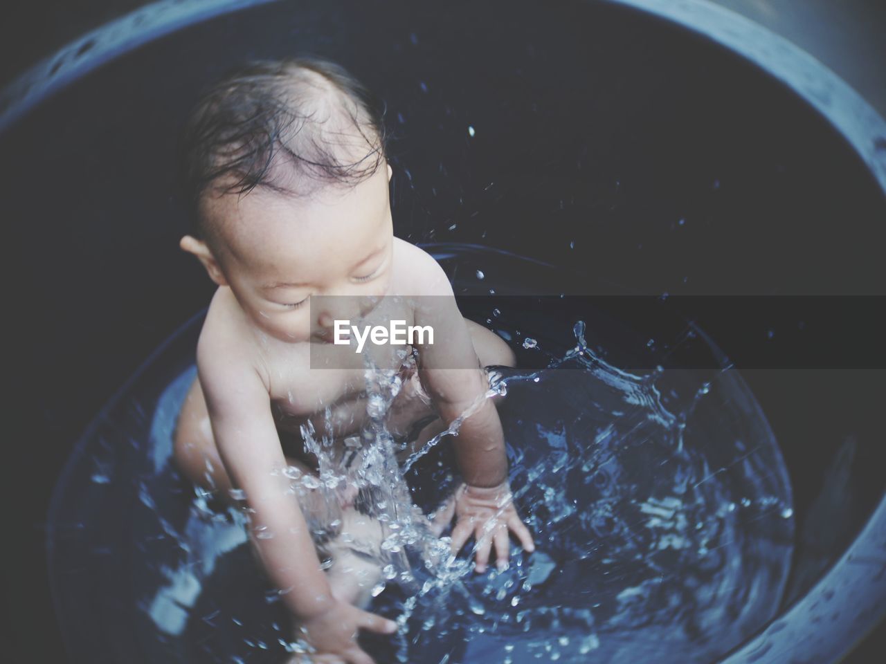 Full length of cute baby boy splashing water in bathtub