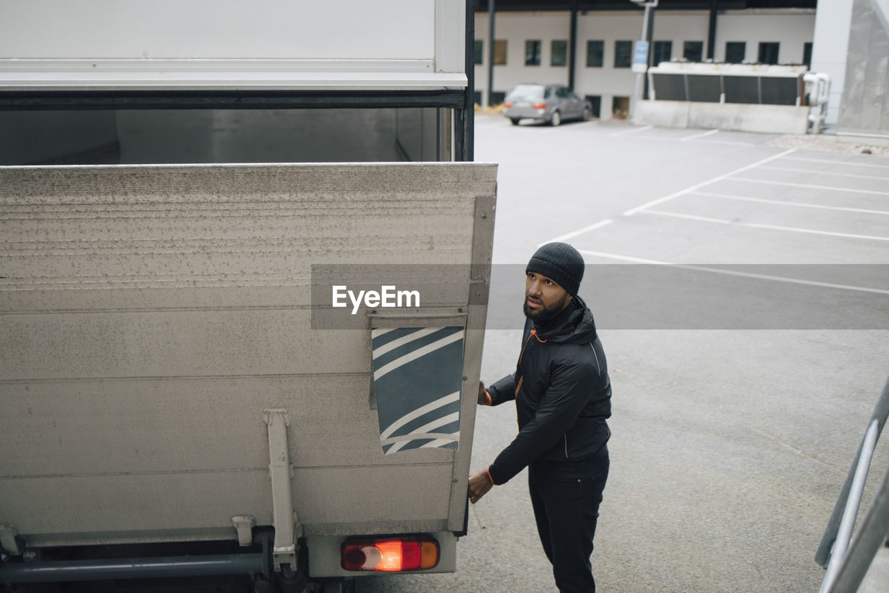 Male worker opening trunk of van while standing on street