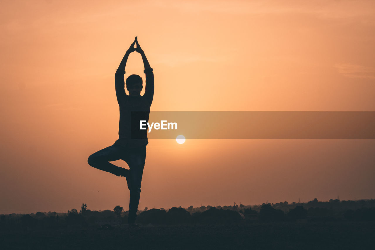 SILHOUETTE MAN WITH ARMS OUTSTRETCHED AGAINST SKY DURING SUNSET