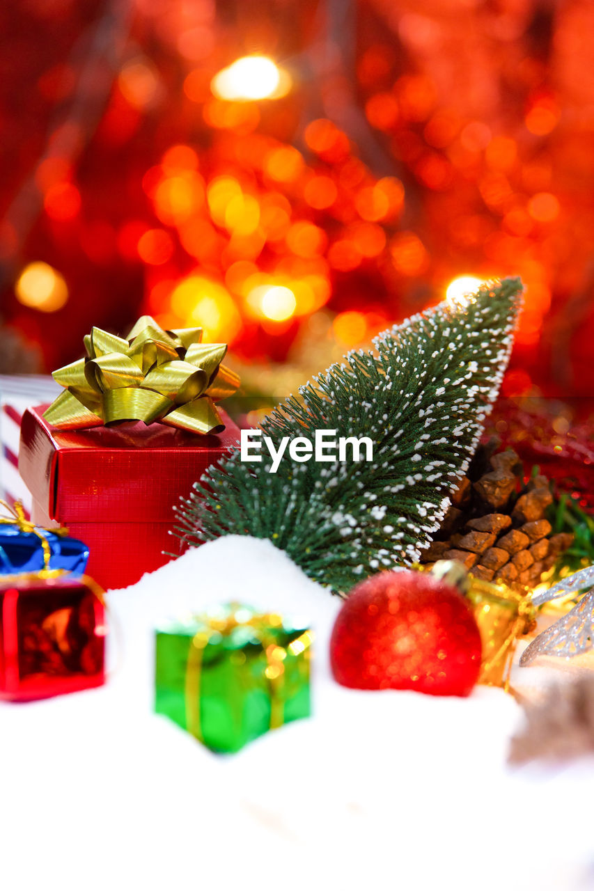 Close-up of christmas presents and decorations on fake snow against defocused lights