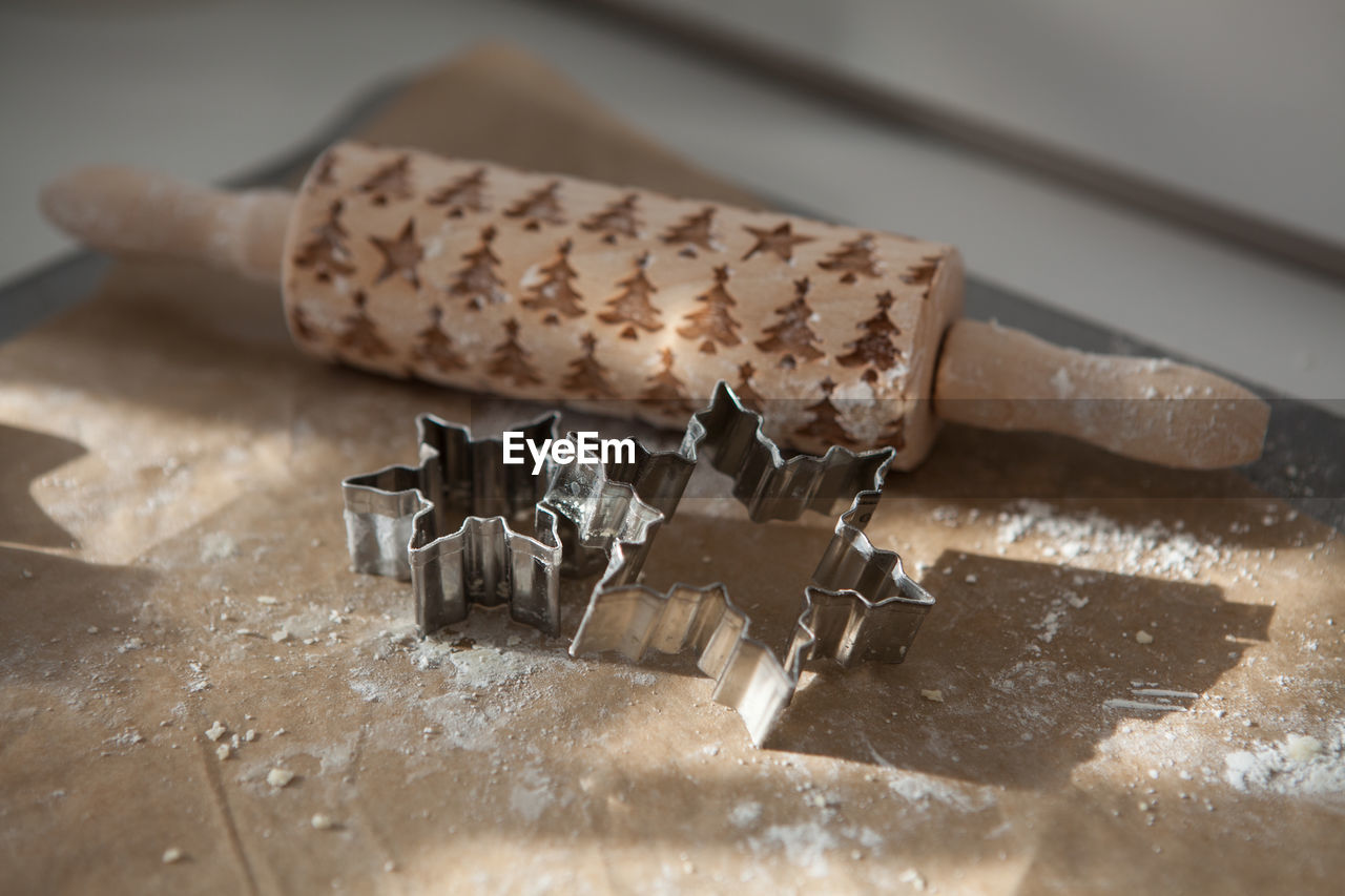 High angle view of rolling pin and cookie cutters on cutting board