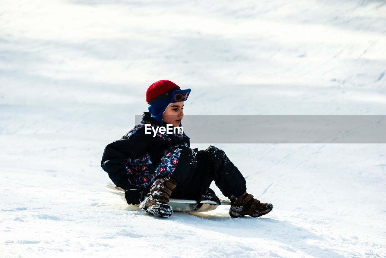 Boy on snow covered field during winter