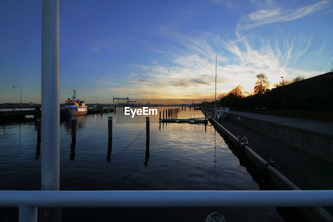 Harbor against sky at sunset