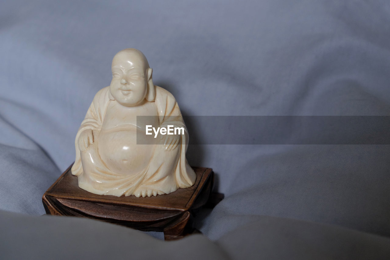 Close-up of buddha figurine on bed