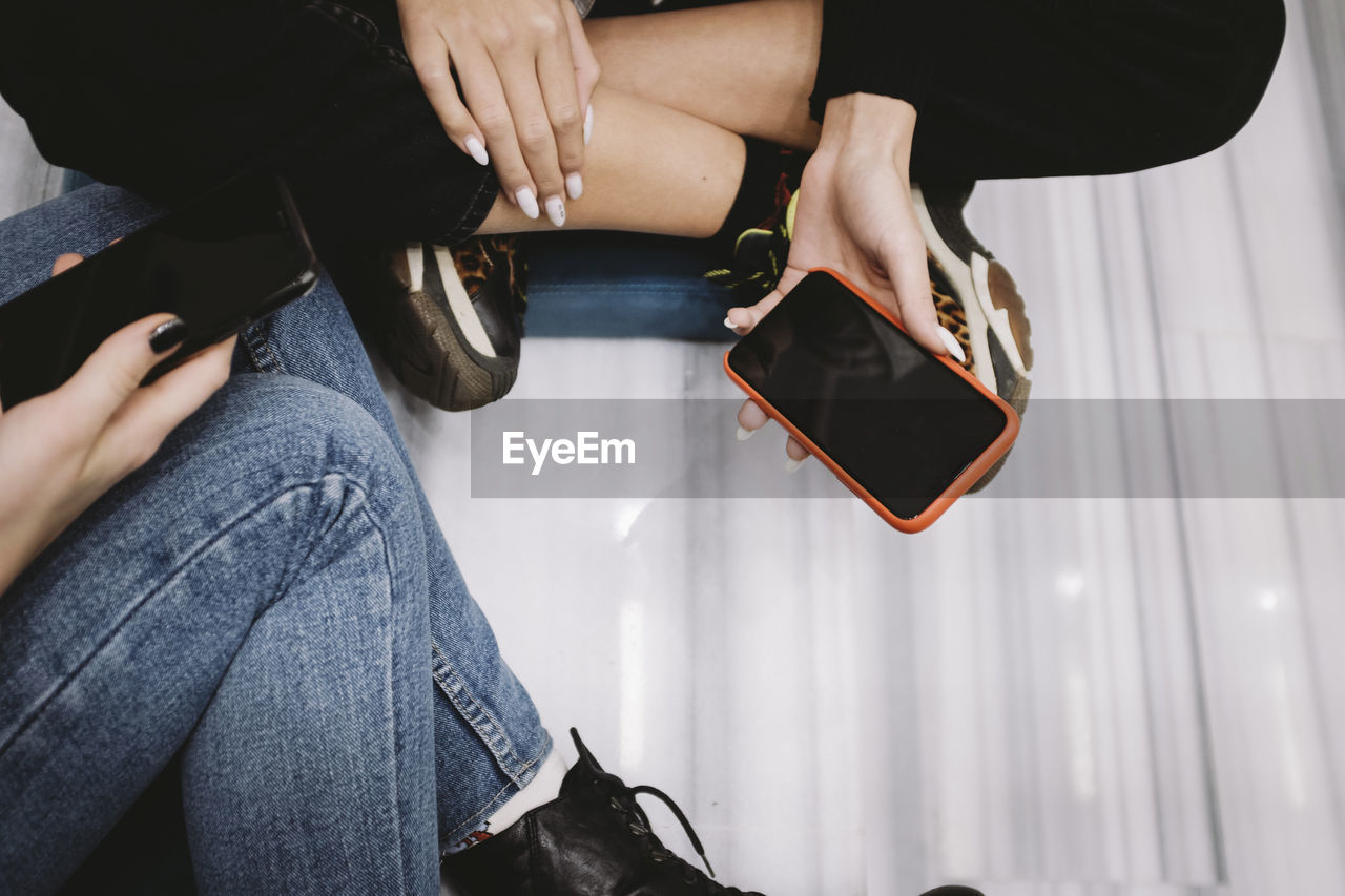Midsection of women using mobile phone