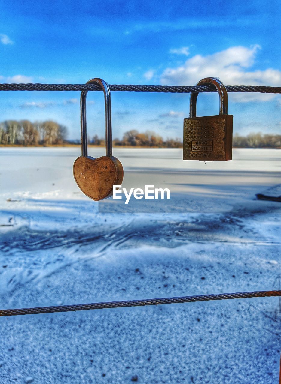 CLOSE-UP OF PADLOCK ON RAILING AGAINST SKY