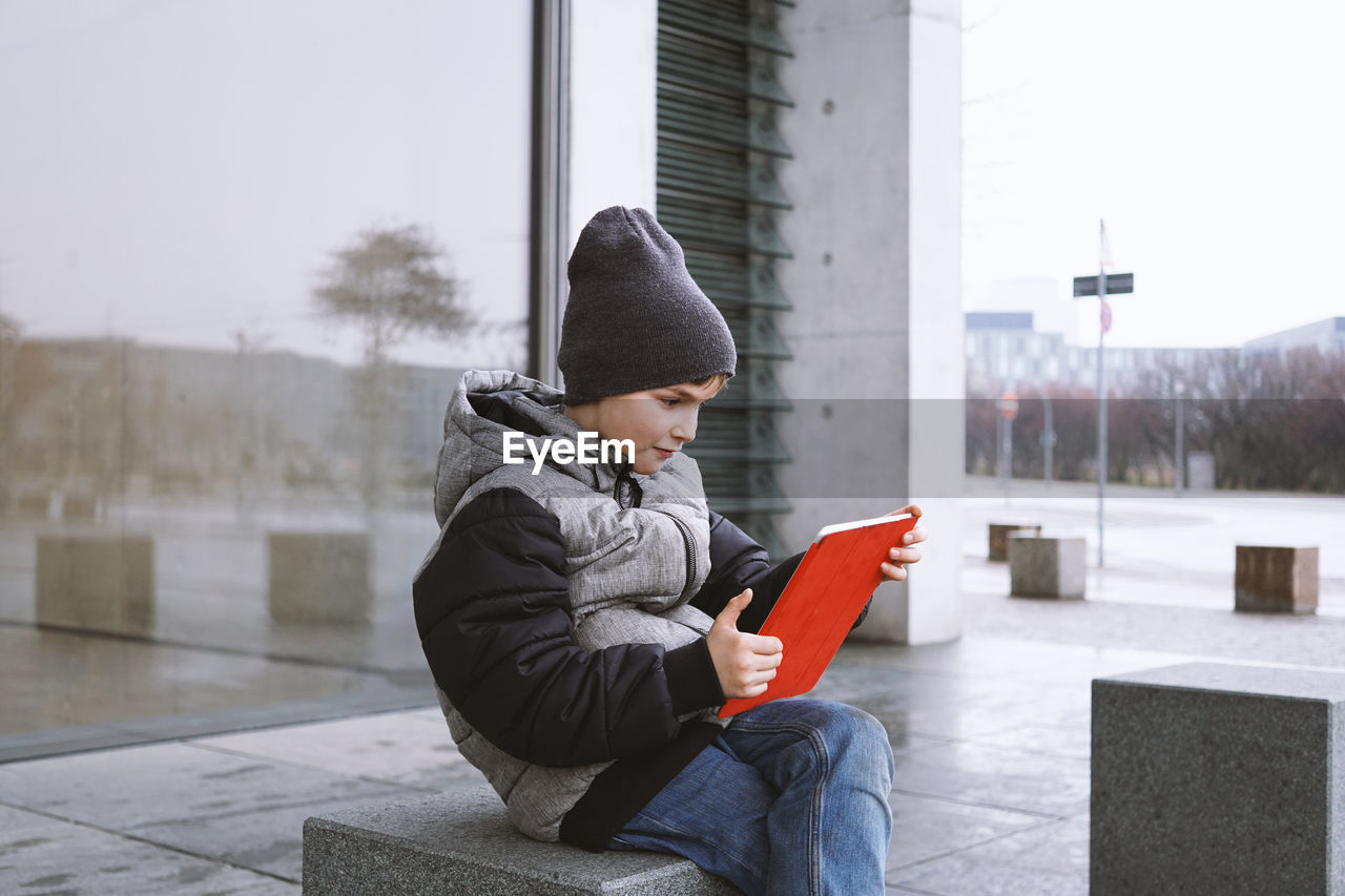 Boy using digital tablet on seat