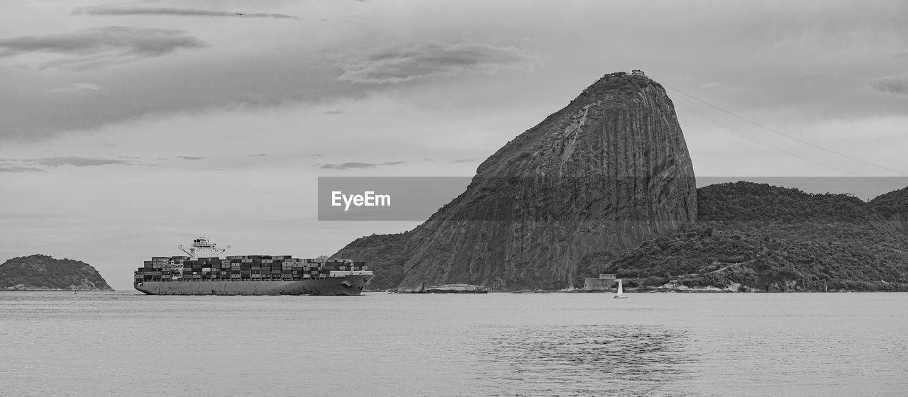 Photo of sugarloaf mountain with a cargo ship passing in front of it in guanabara bay
