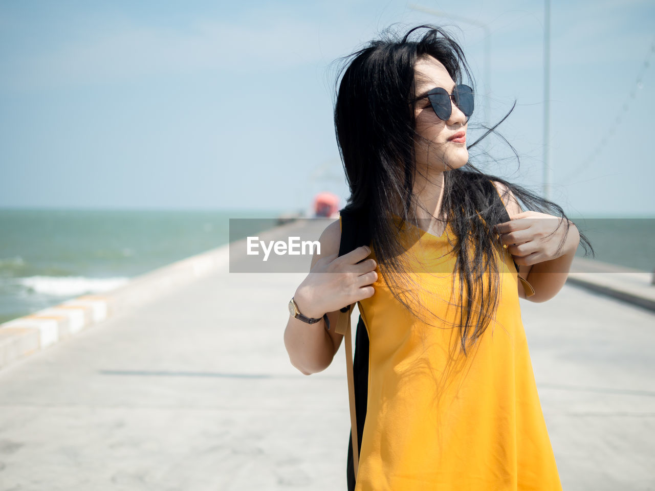Young woman wearing sunglasses while standing by sea