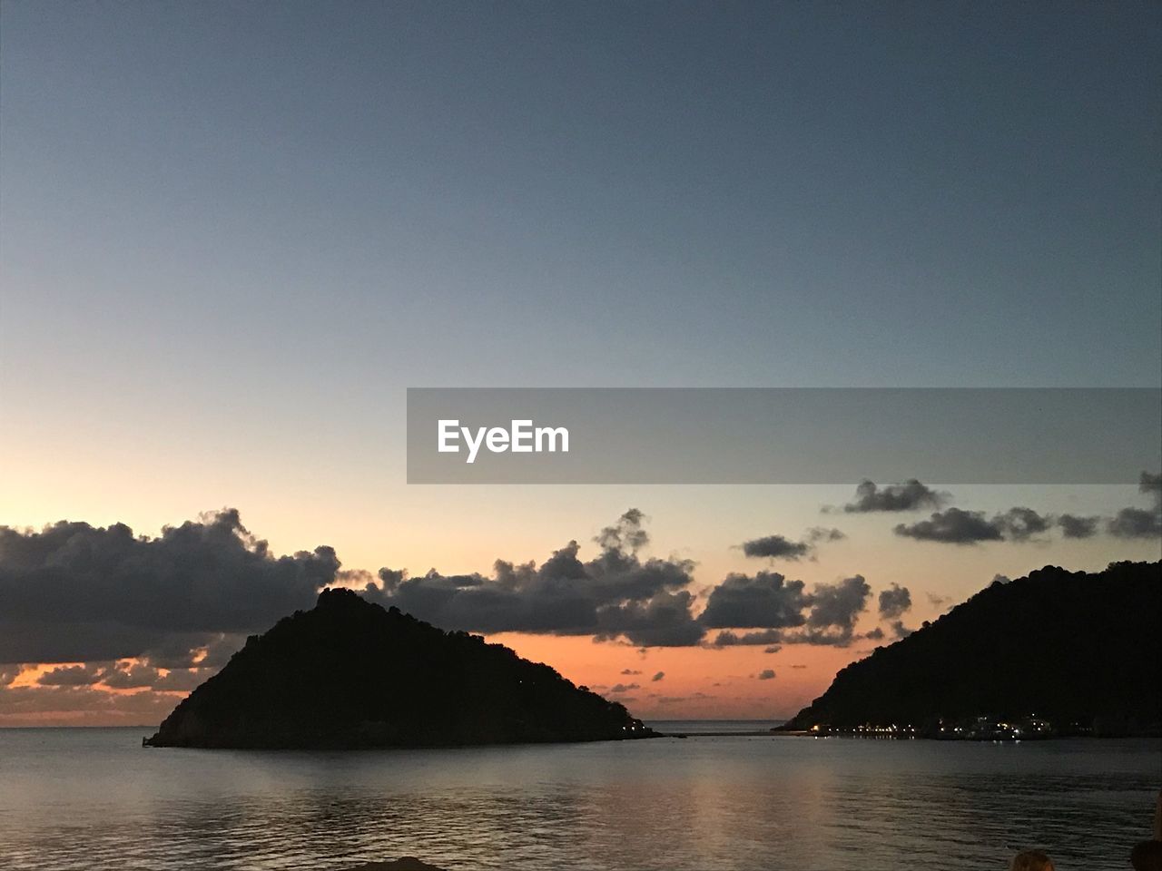 SCENIC VIEW OF SEA BY SILHOUETTE MOUNTAIN AGAINST SKY