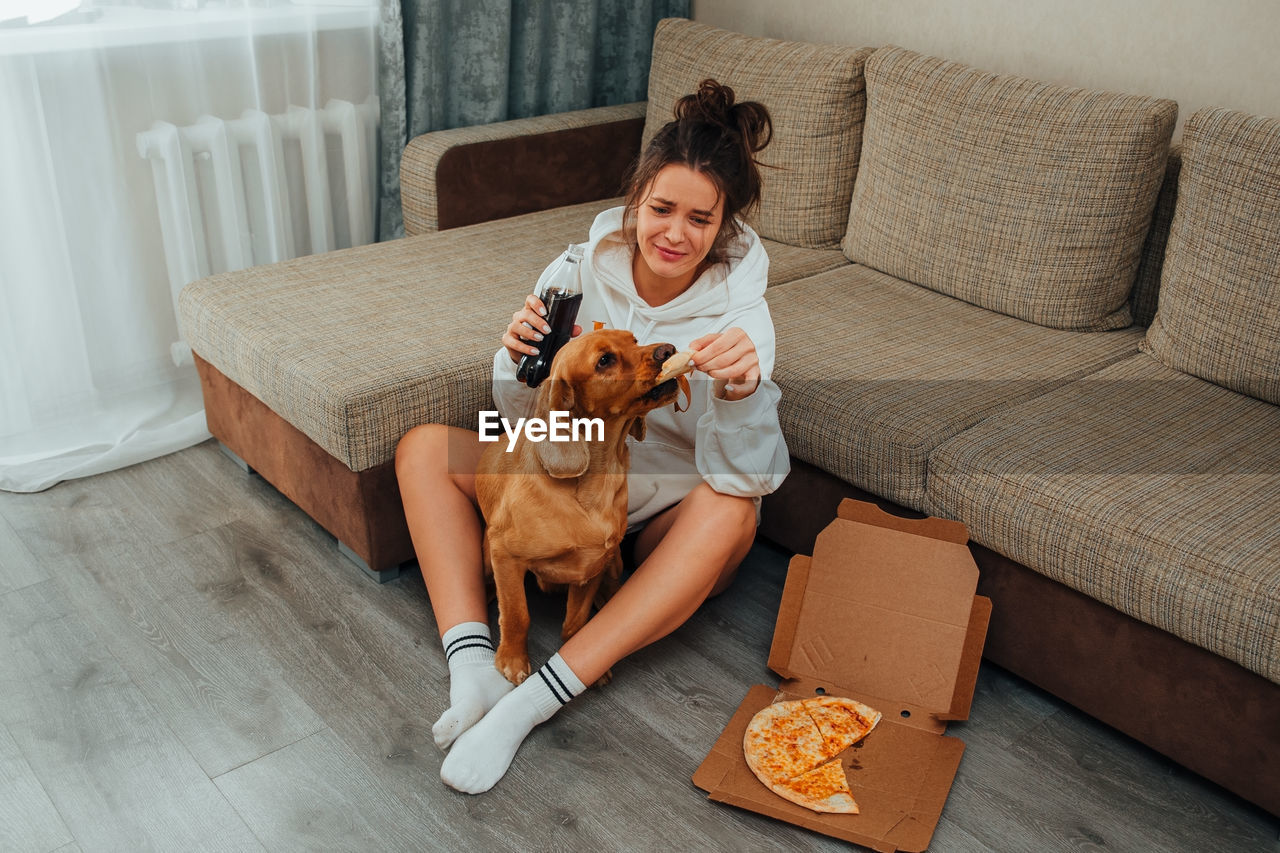 YOUNG WOMAN WITH DOG ON SOFA
