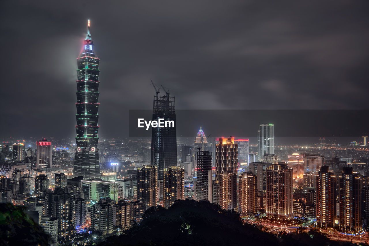 Illuminated modern buildings against sky at night