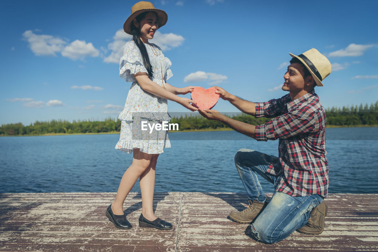 WOMAN WEARING HAT AGAINST LAKE AGAINST SKY