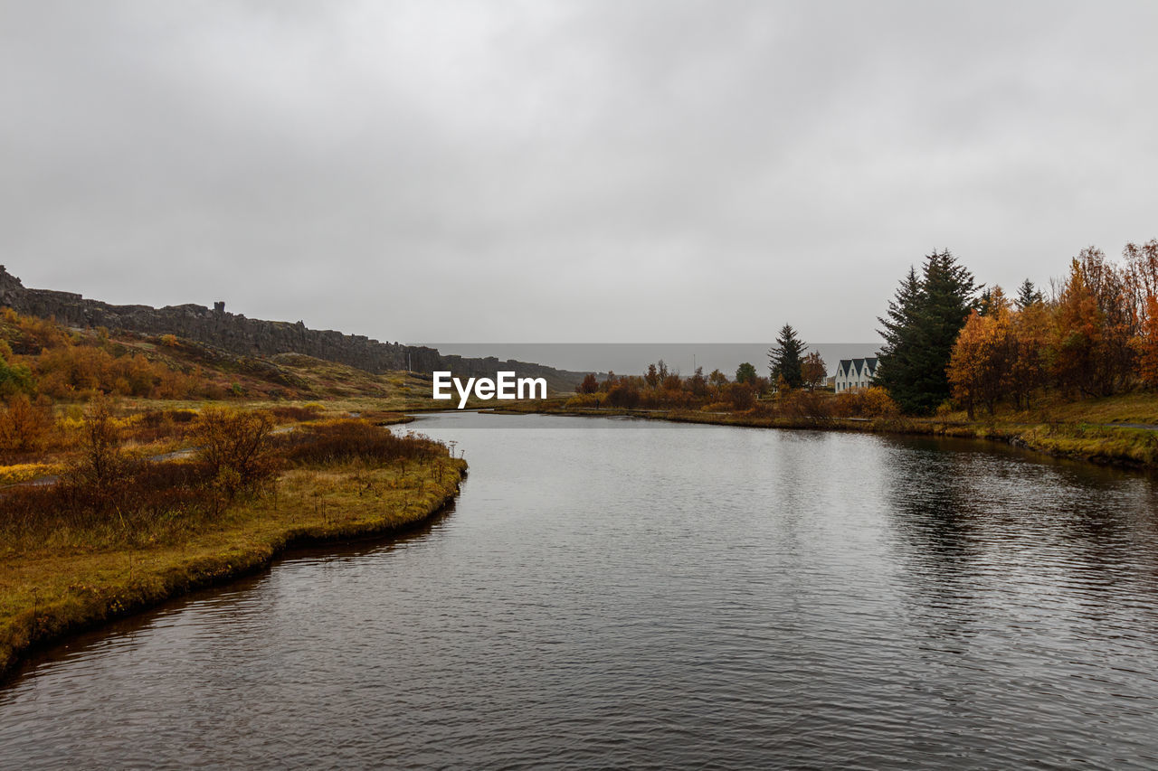 Scenic view of river by mountains against sky