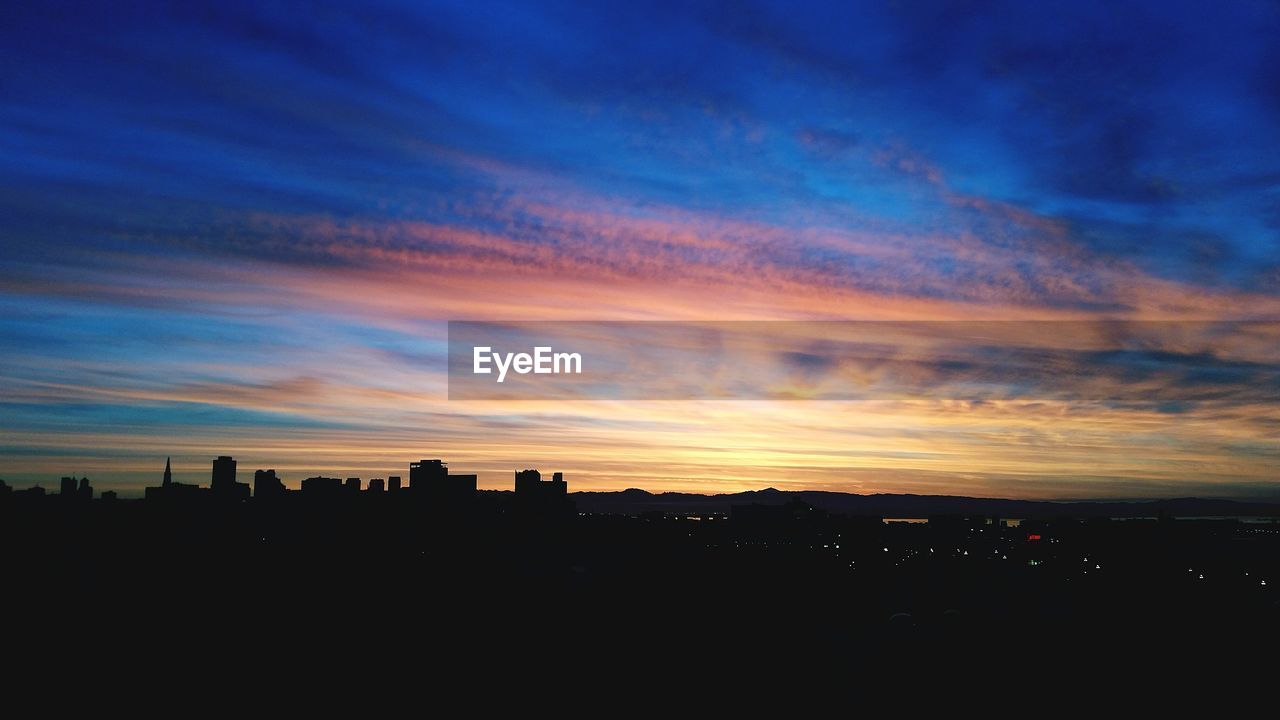 Silhouette landscape against cloudy sky during sunset