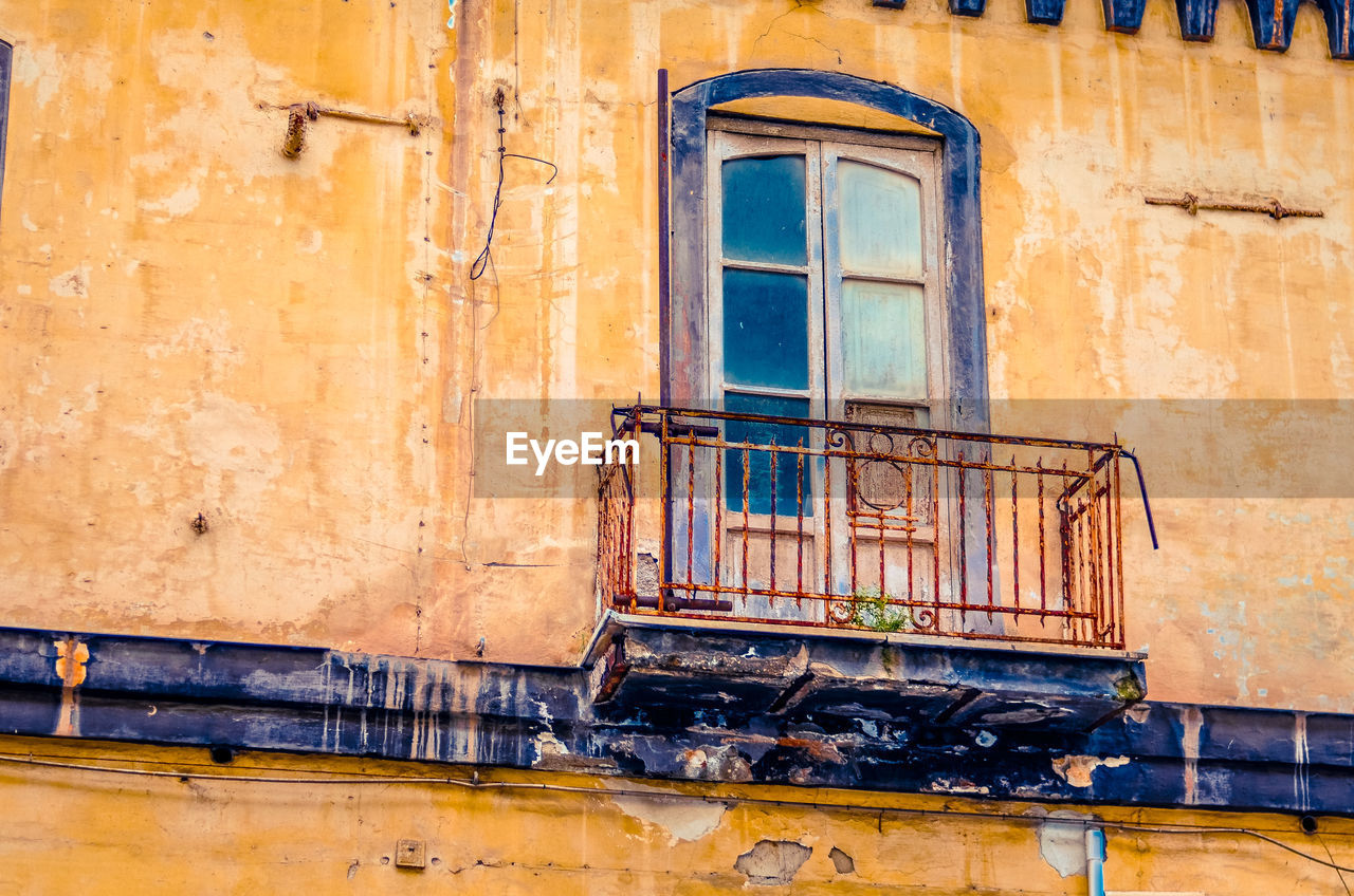 Vintage balcony on an old abandoned and decaying house facade in italy