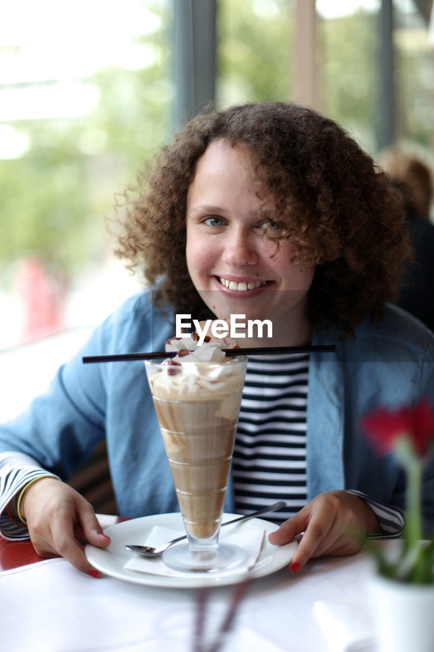 Portrait of smiling young woman sitting on table