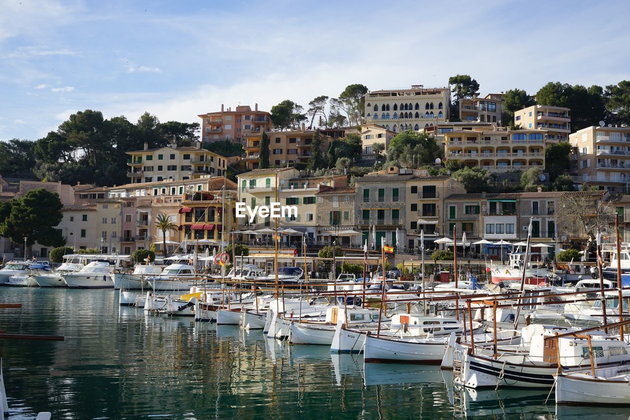 Boats moored at harbor against buildings in city