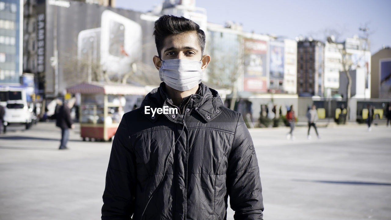 Portrait of young man standing on city street
