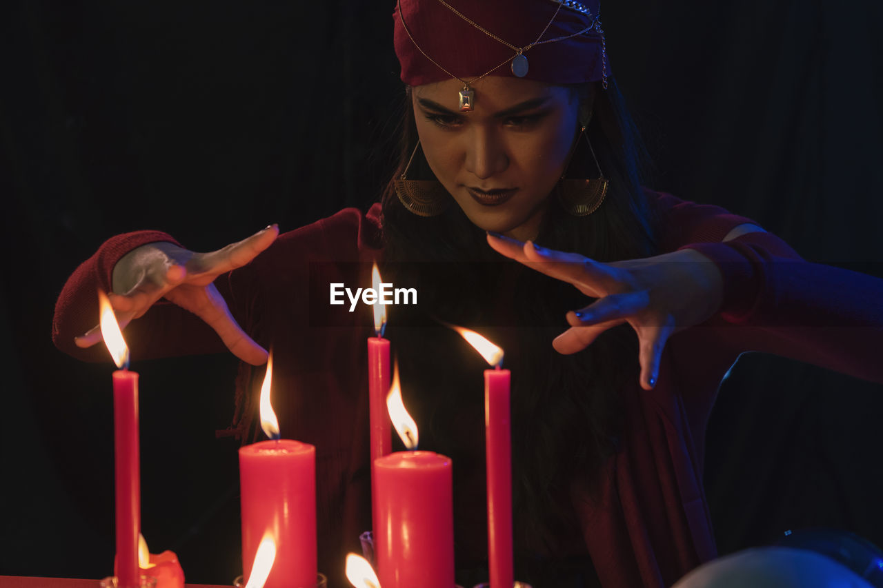 Female fortune teller with burning candles at home