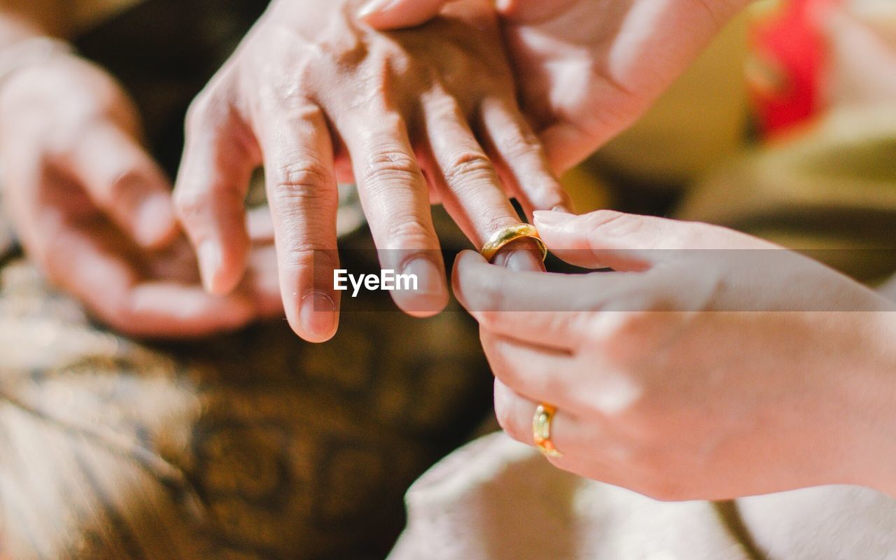 Cropped image of woman putting ring in finger of mother