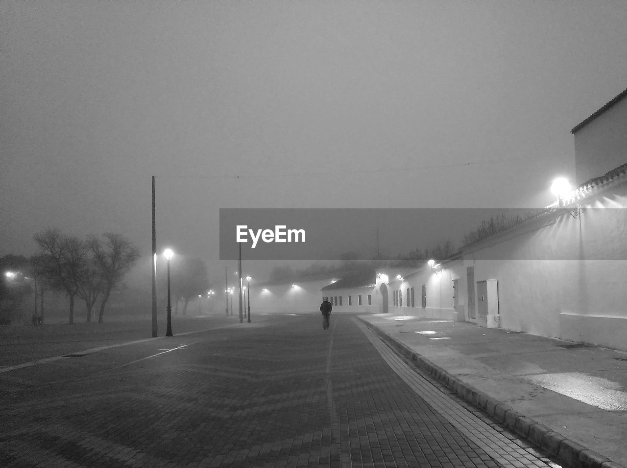 Illuminated street lights on road against sky at night