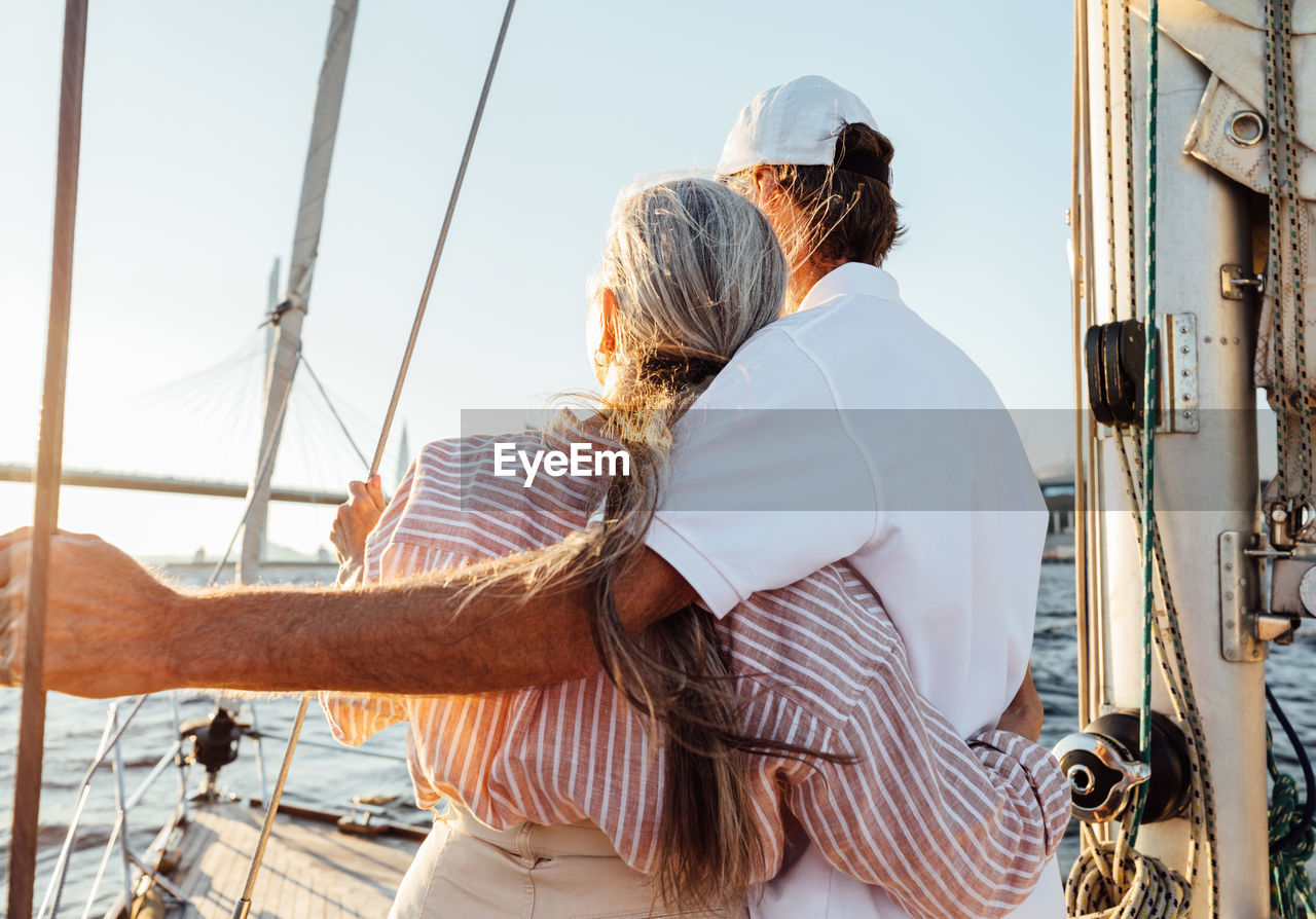 Rear view of women sailing on sea against sky