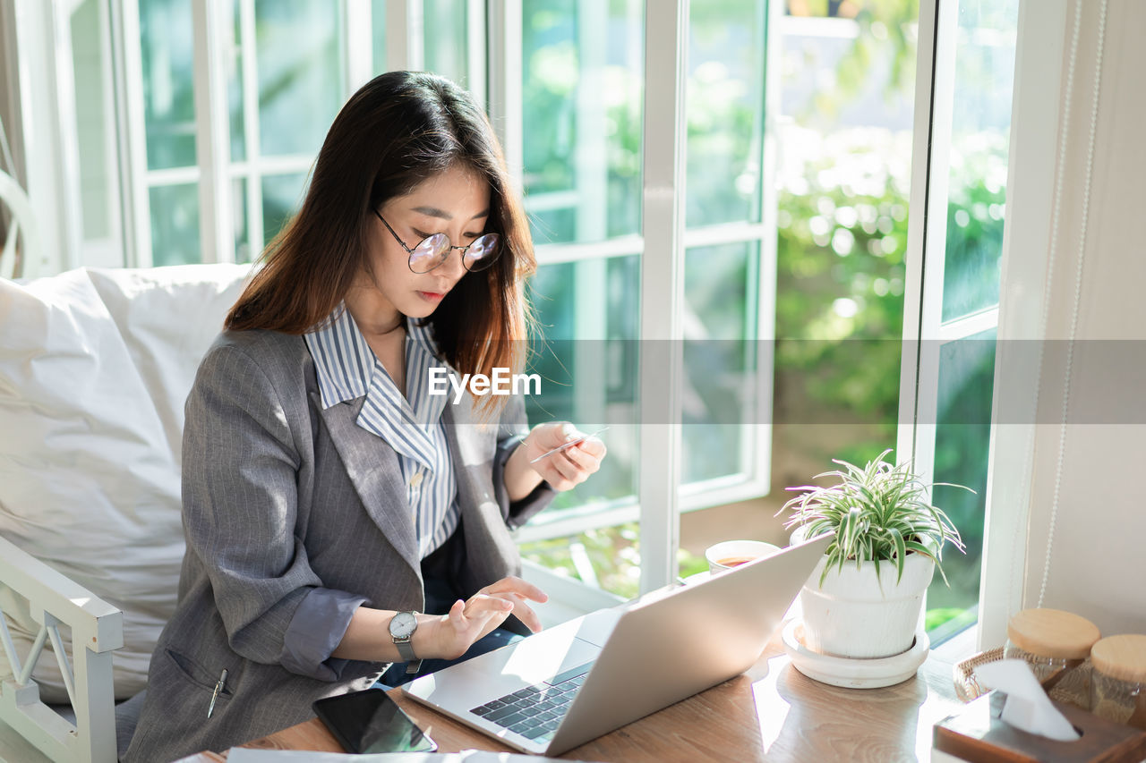 Young woman using phone while sitting on table