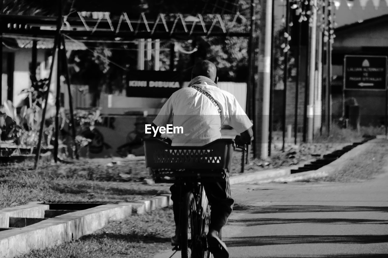 FULL LENGTH REAR VIEW OF MAN RIDING BICYCLE ON STREET