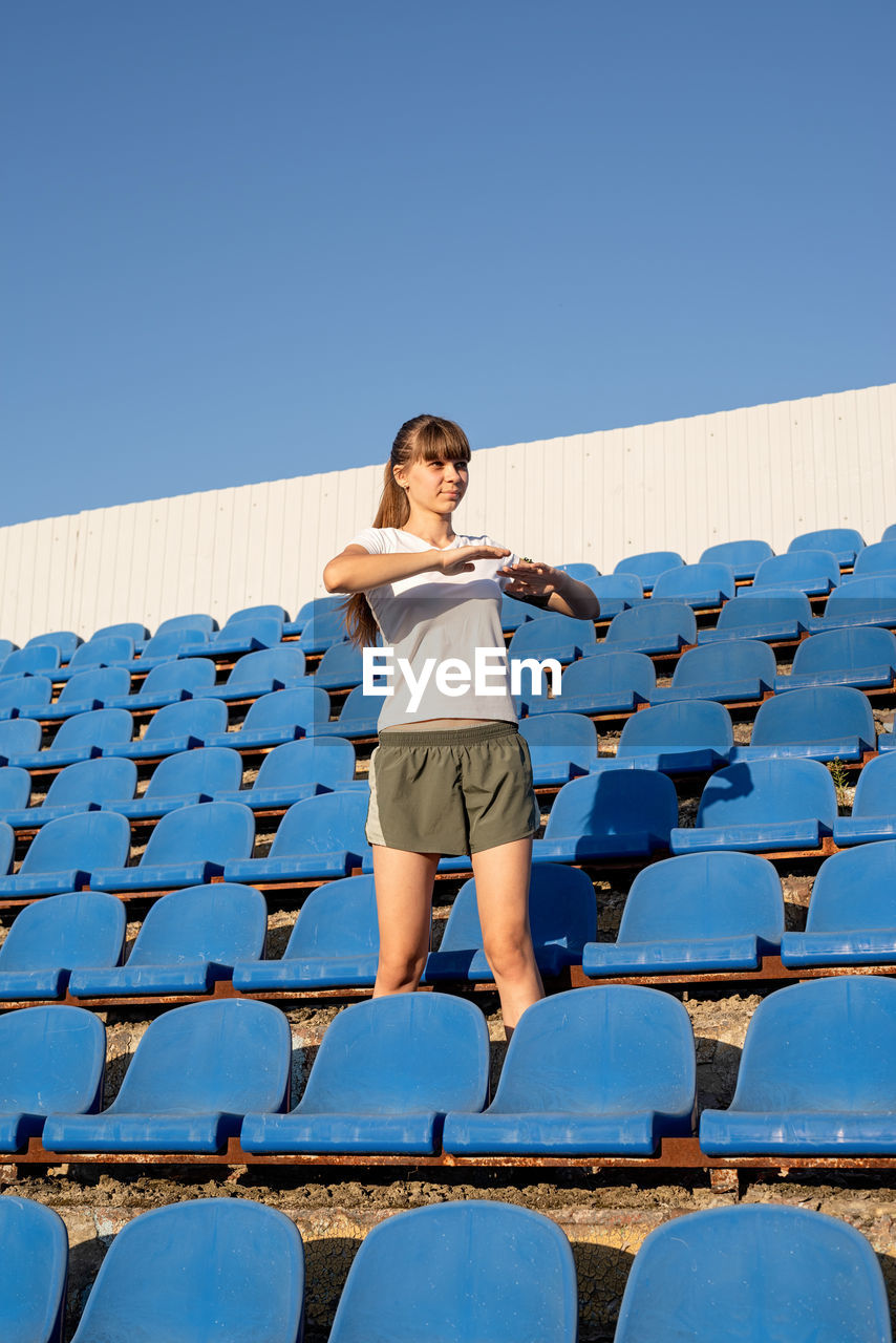 Full length of woman standing against clear blue sky