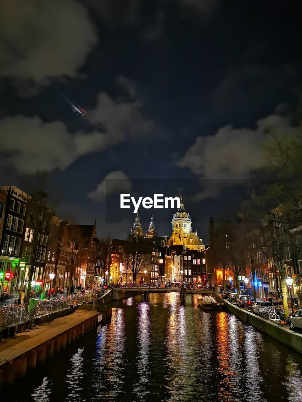 ILLUMINATED BUILDINGS BY RIVER AGAINST SKY AT NIGHT IN CITY