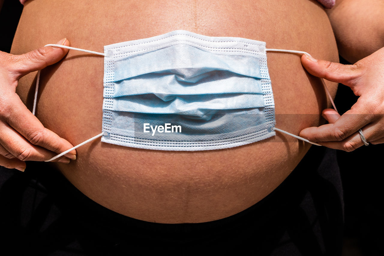 Midsection of woman holding mask