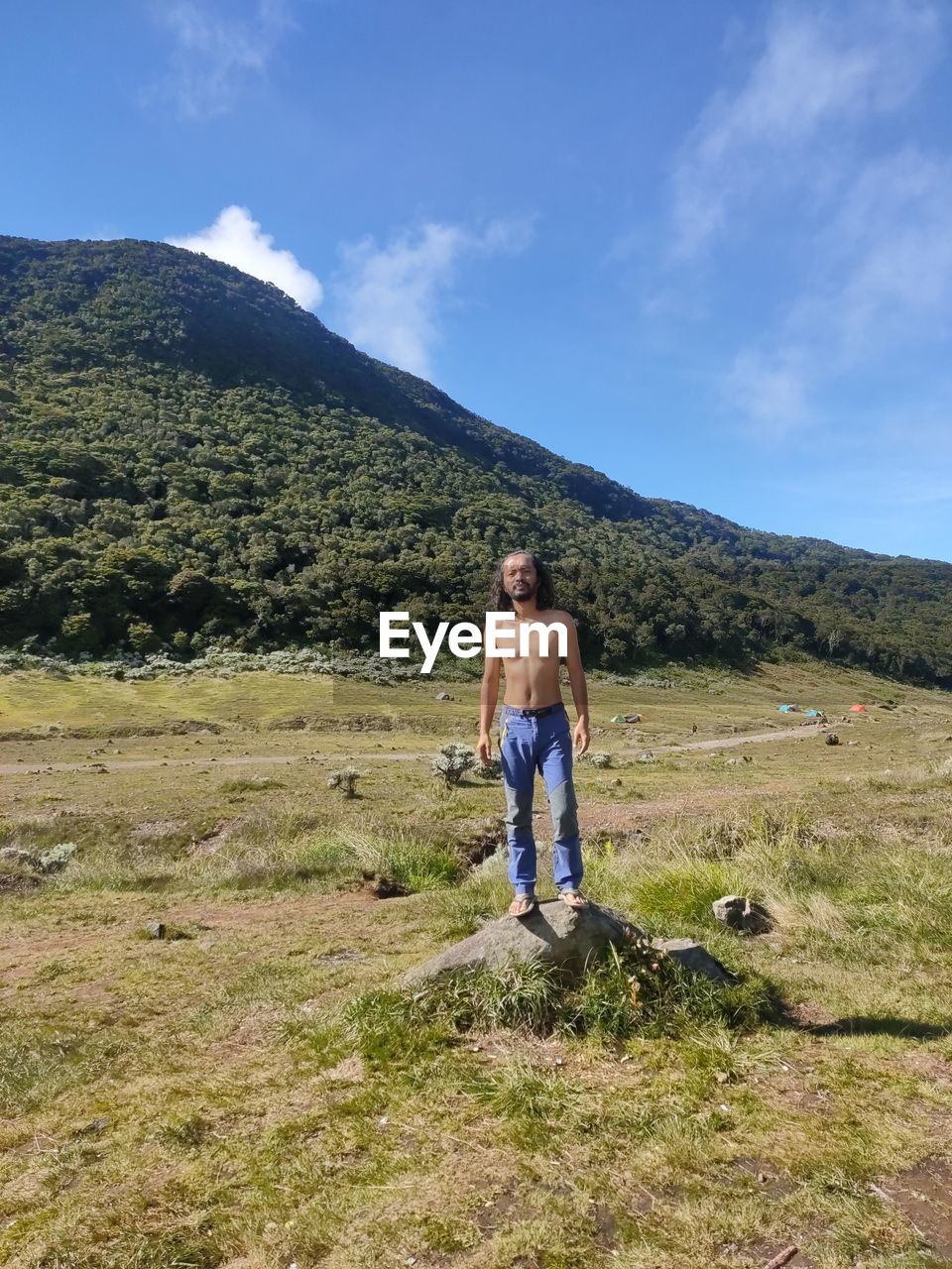 mountain, sky, leisure activity, full length, nature, landscape, adult, environment, men, scenics - nature, beauty in nature, grass, plant, hiking, walking, land, activity, lifestyles, holiday, adventure, vacation, wilderness, travel, trip, casual clothing, day, two people, ridge, mountain range, cloud, non-urban scene, togetherness, sports, standing, front view, outdoors, women, young adult, backpack, tranquility, blue, travel destinations, recreation, sunlight, emotion, tranquil scene, idyllic, rural scene, exploration, tourism, summer, backpacking, remote, friendship, tree, green