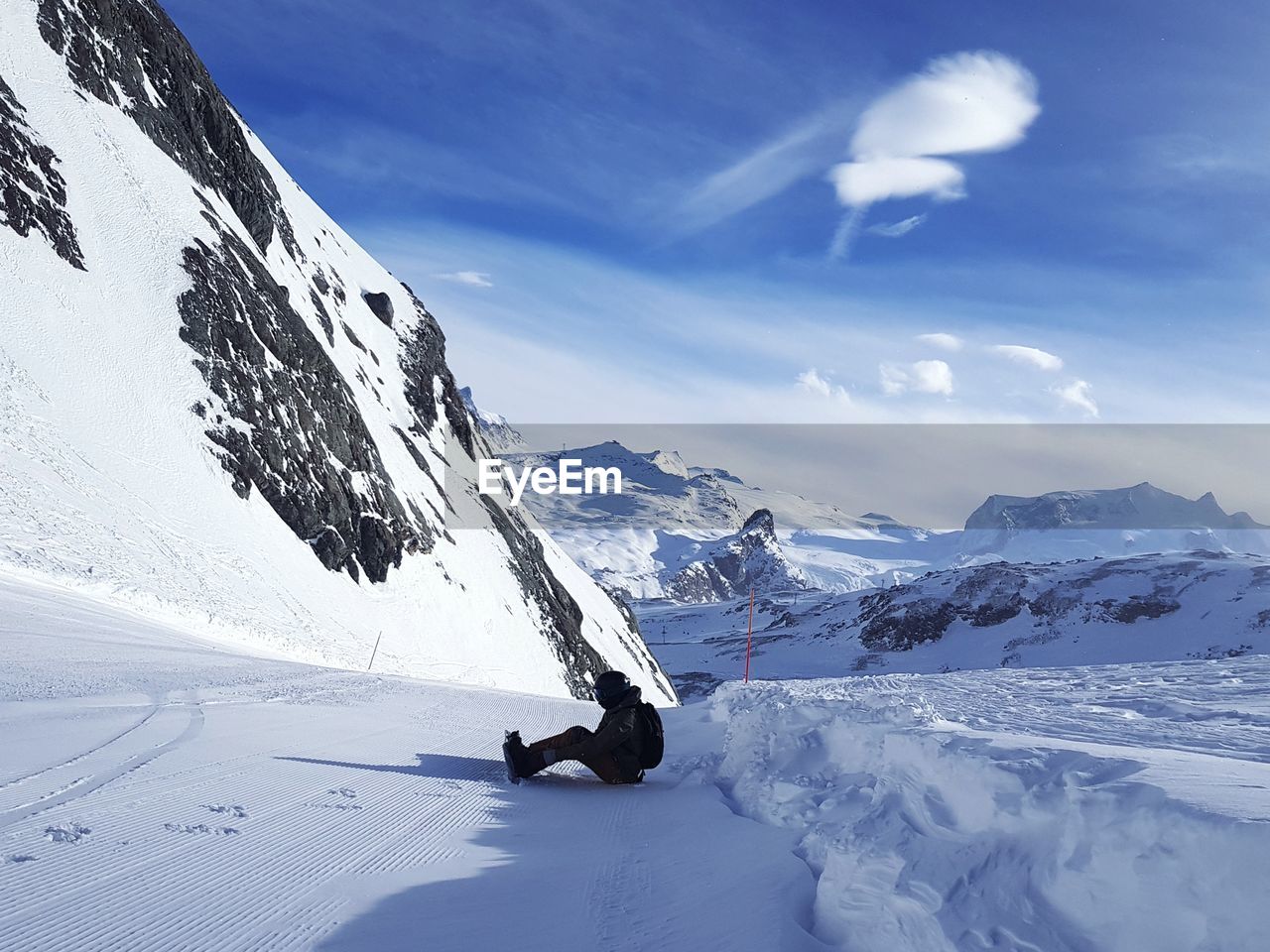 MAN ON SNOWCAPPED MOUNTAIN AGAINST SKY