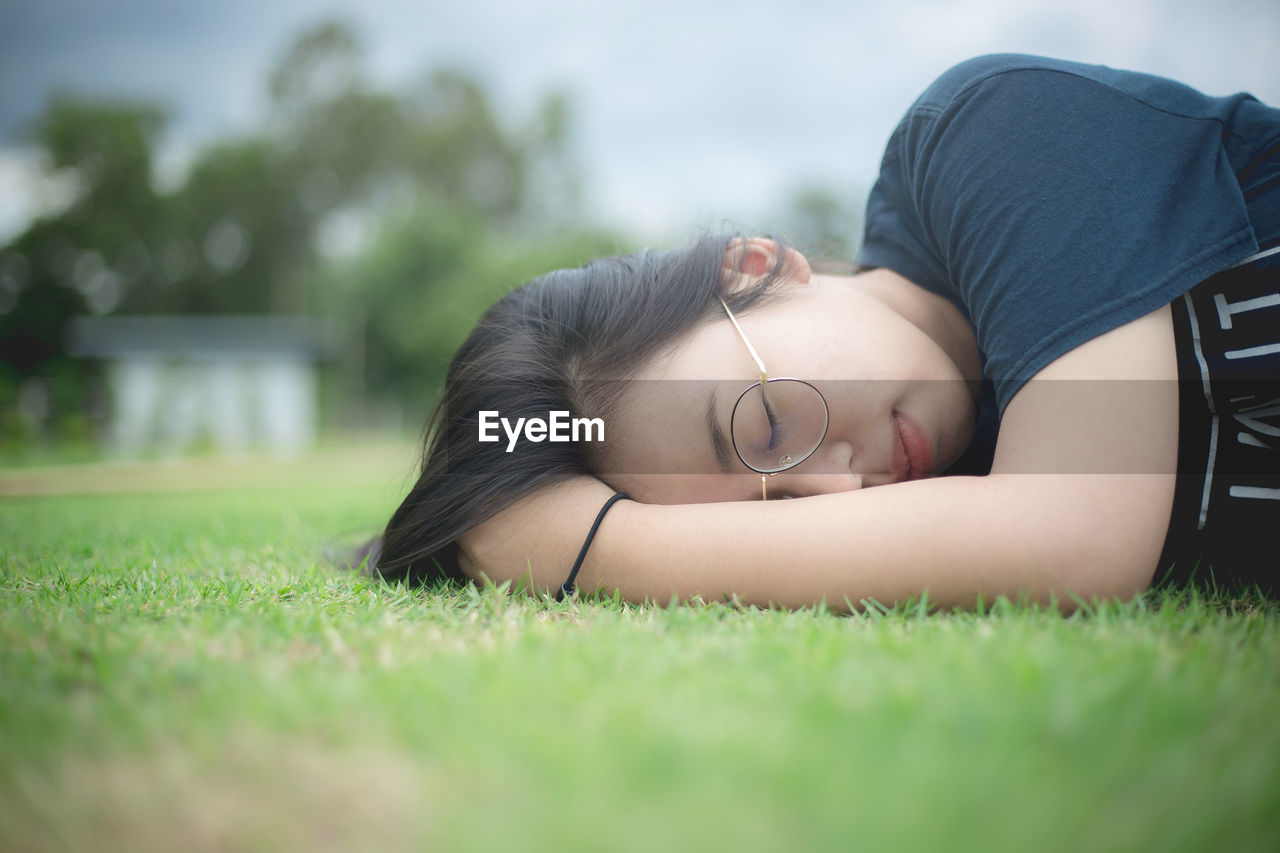Young woman with hand in hair sleeping on grass