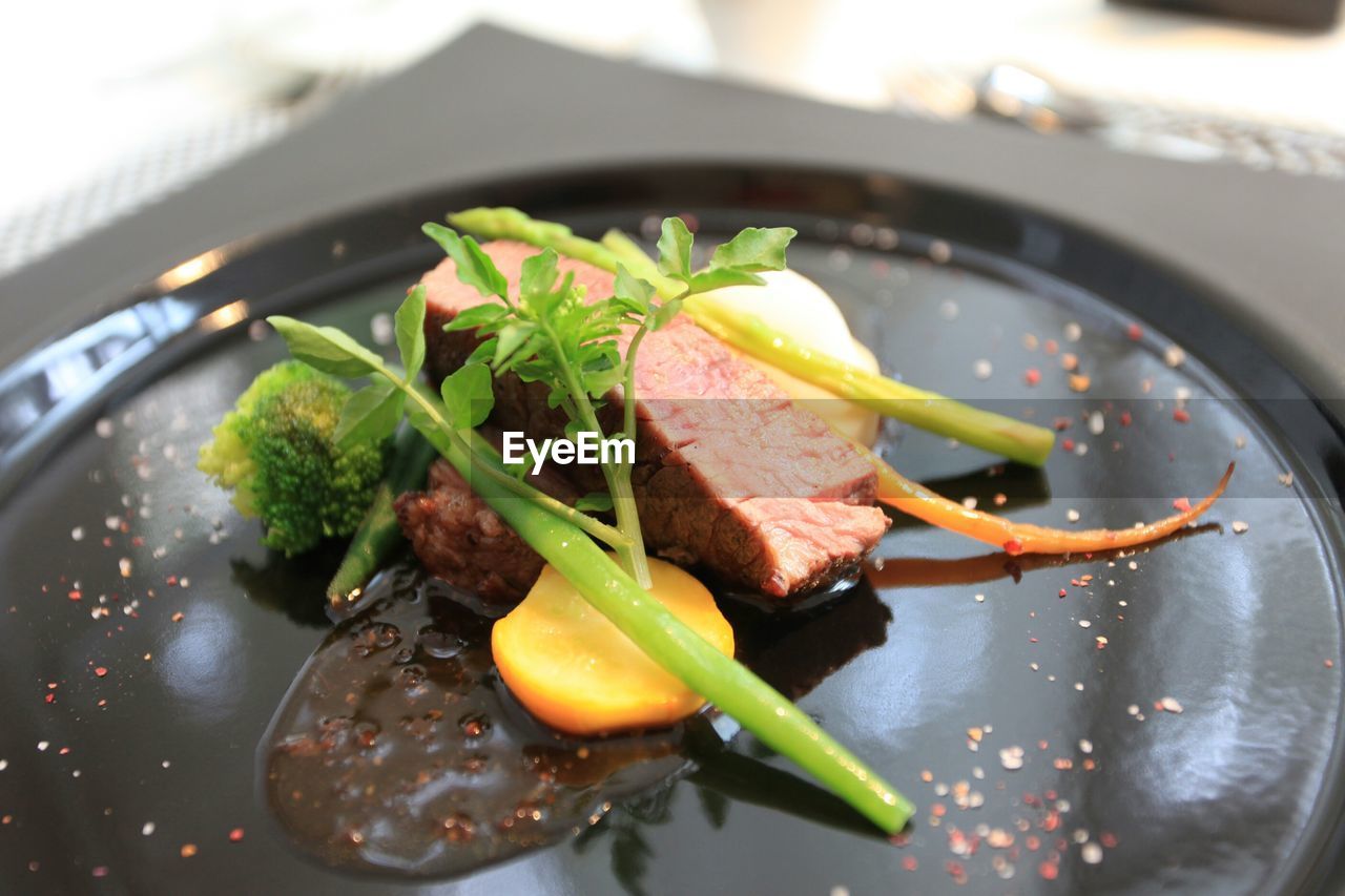 Close-up of meat slice with vegetable in plate