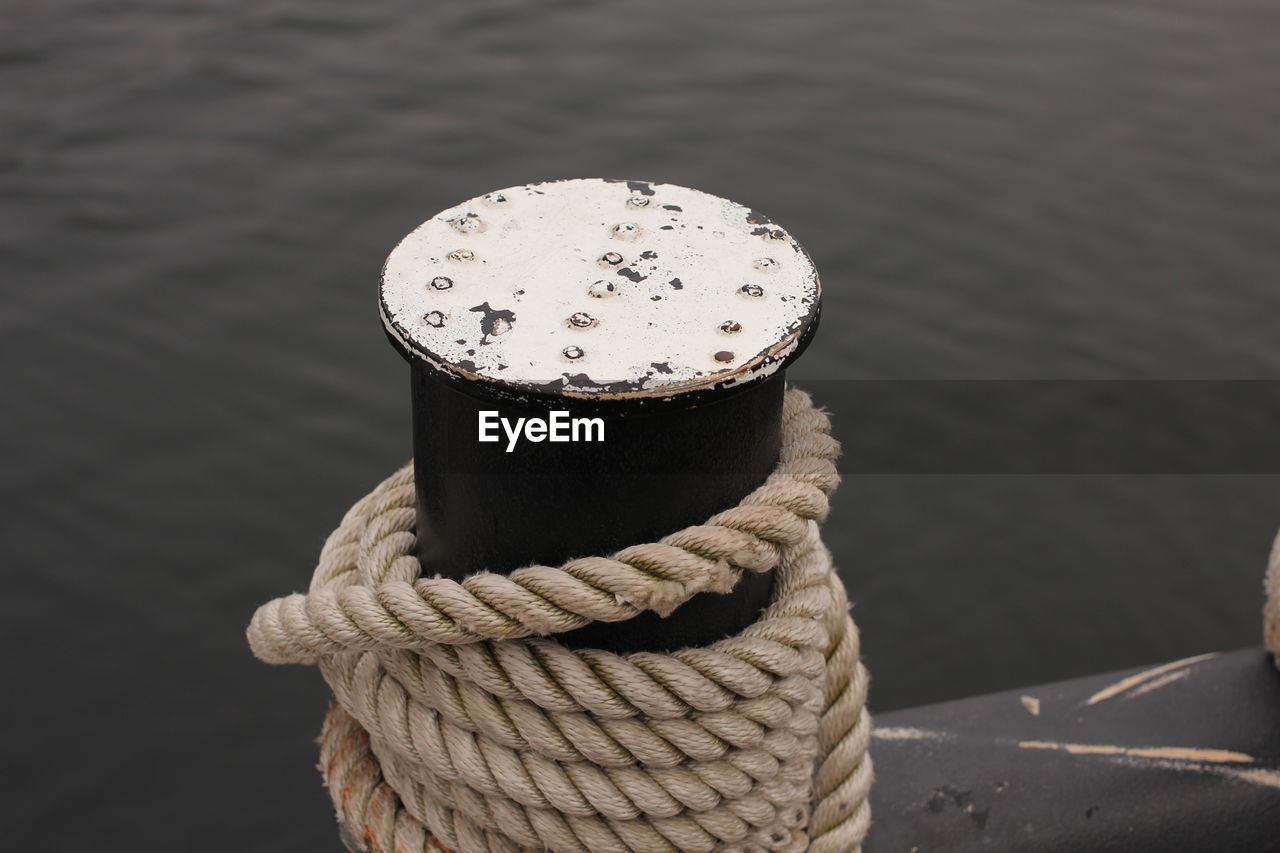 Close-up of rope on bollard against sea