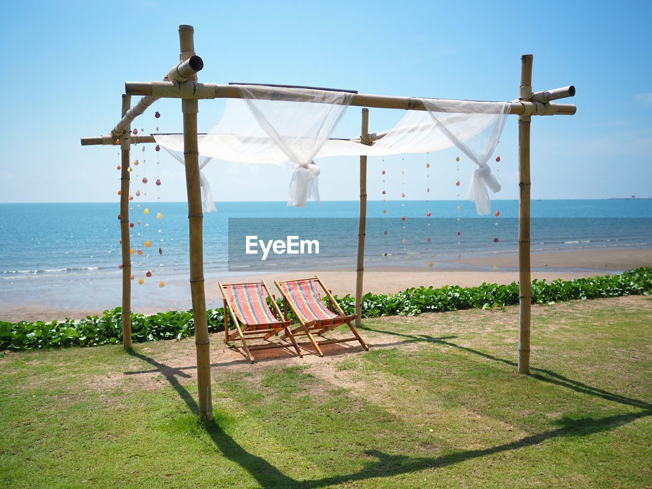 Entertainment tent with chairs at beach against clear blue sky